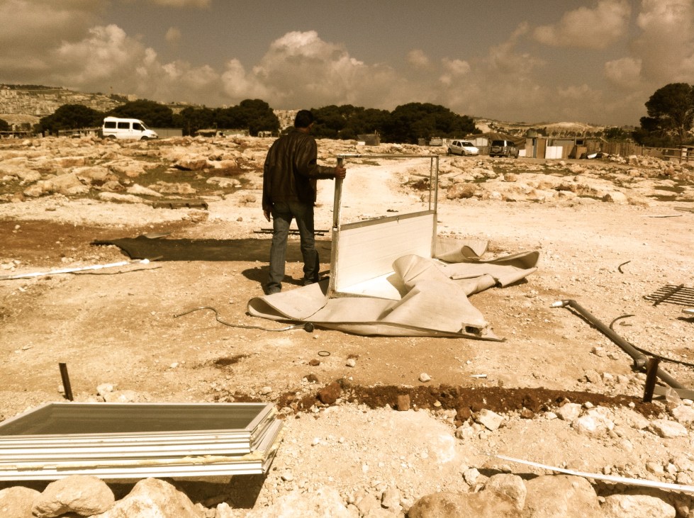 A man stands next to what remains of his house in the Bedouin village of Jabal al-Baba in the West Bank. Recently, Amira Hass reported on government plans to forcibly transfer up to 12,500 Bedouins living in the West Bank and East Jerusalem.  