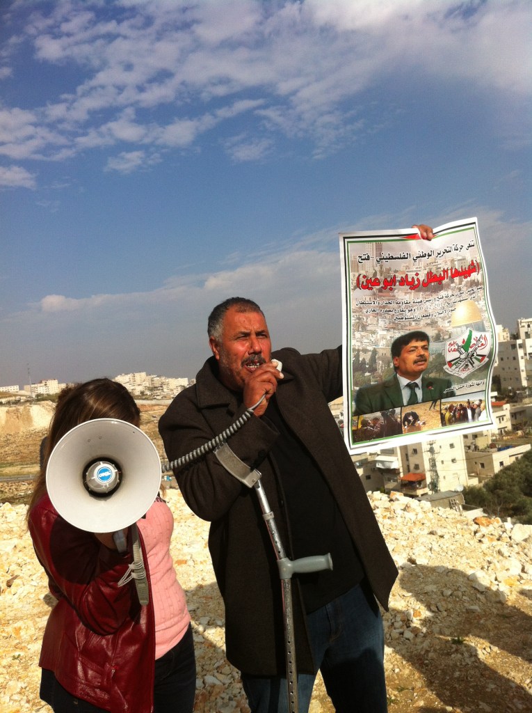 Mohammad Abu Hummus holding up a poster of Ziad Abu Ein